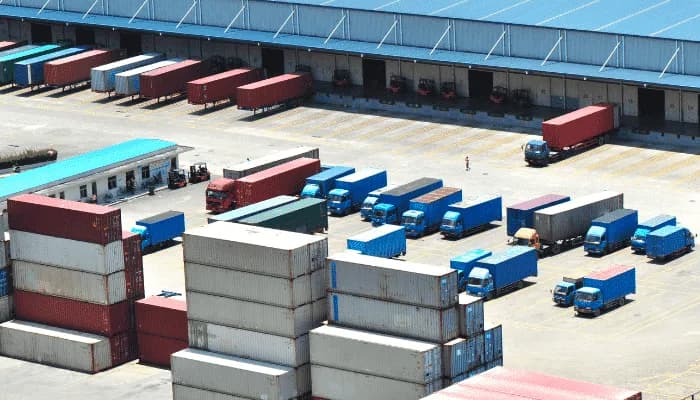 containers and truck at shipping port with warehouse in the background